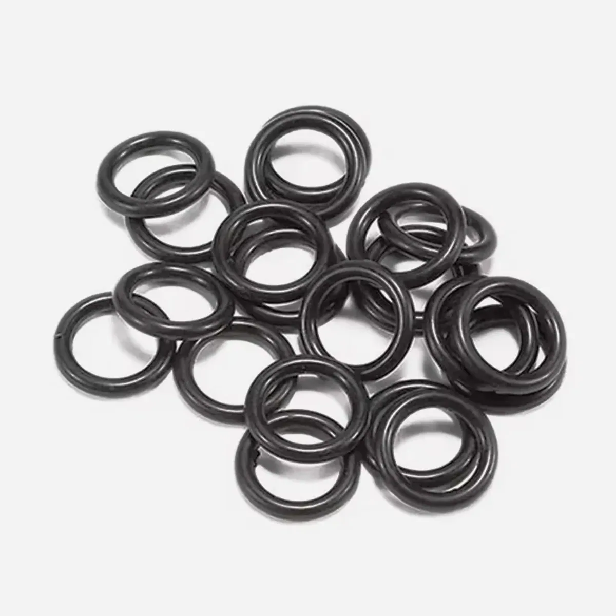 Pile of black rubber O-rings heaped together on a plain light background