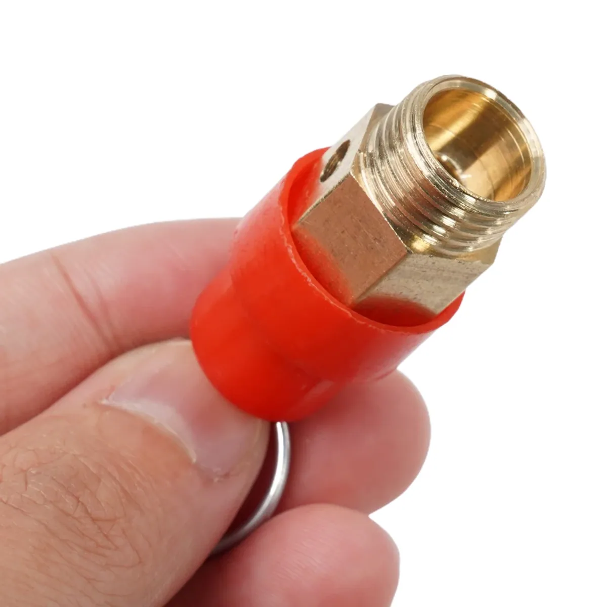 Brass threaded safety valve fitting with a red plastic sleeve held in a hand