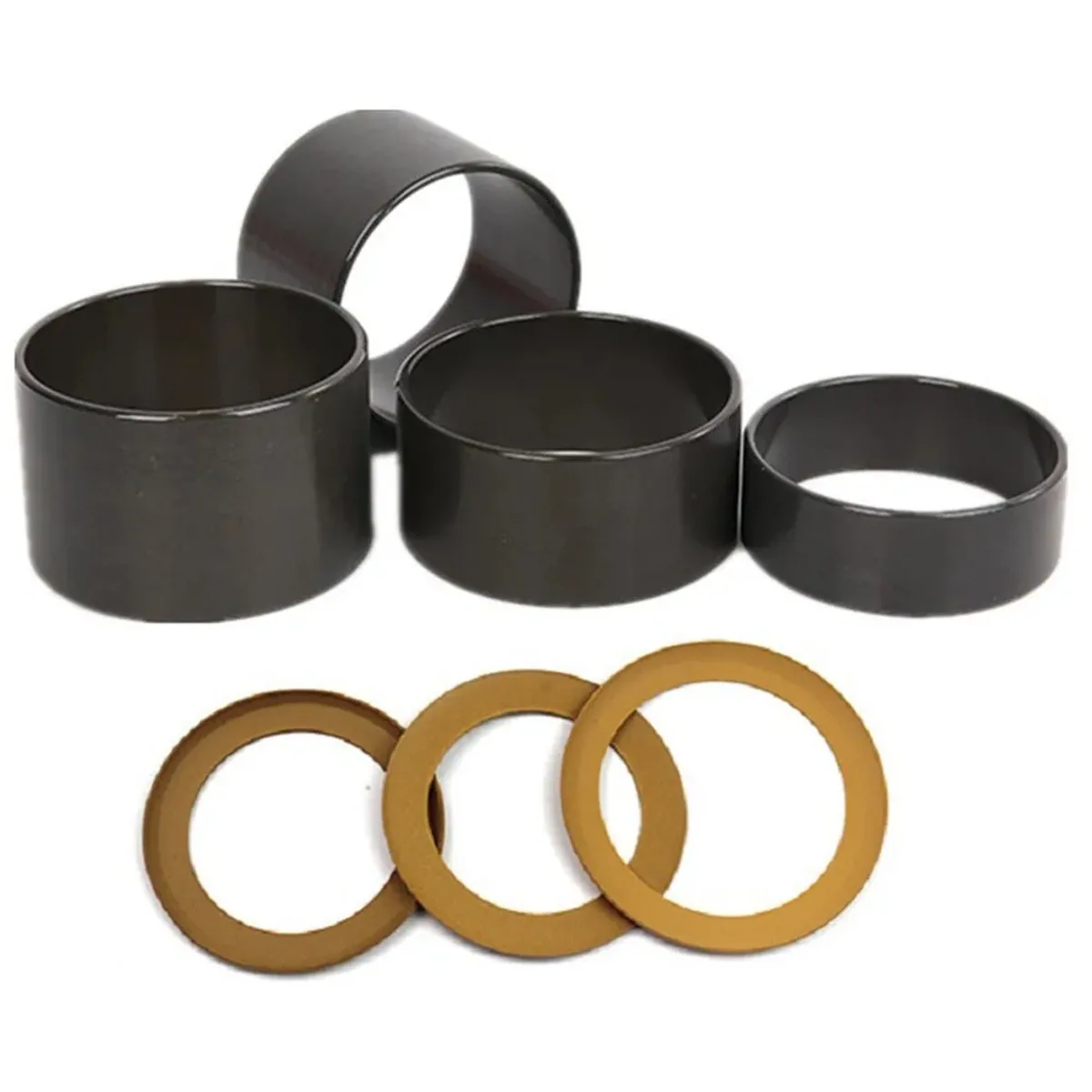 Black metal bushings and gold washers laid out on a plain white background