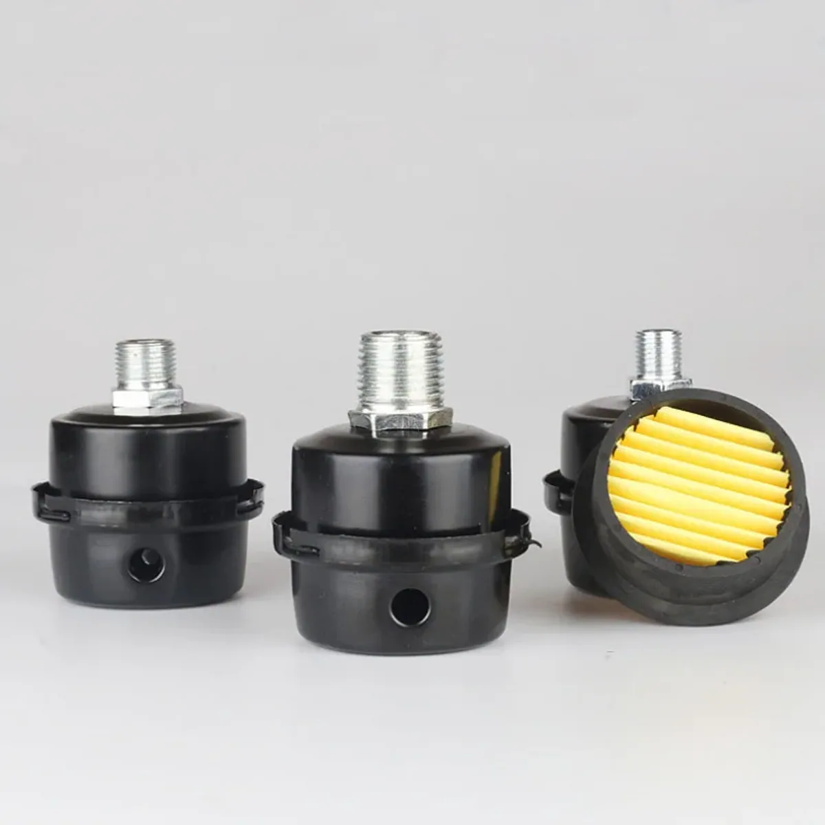 Three black air filter breather units with metal threaded fittings lined up side by side